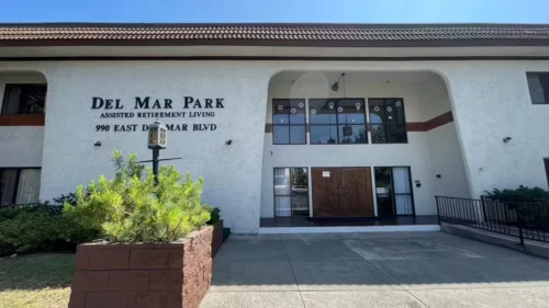 Cozy bedroom with checkered bedspread, wooden furniture, and warm lighting in assisted living facility