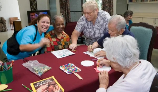 Caregiver smiling with residents during an art therapy session at Jasmin Terrace at El Molino in Pasadena