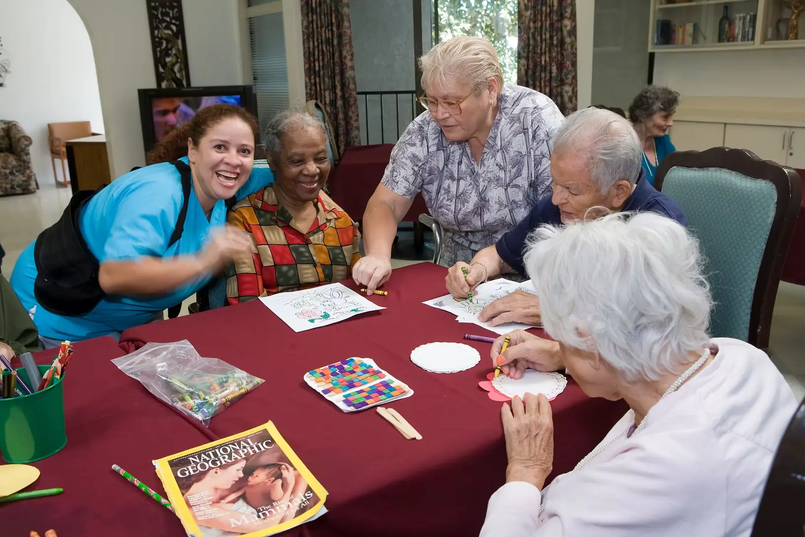 Caregiver smiling with residents during an art therapy session at Jasmin Terrace at El Molino in Pasadena