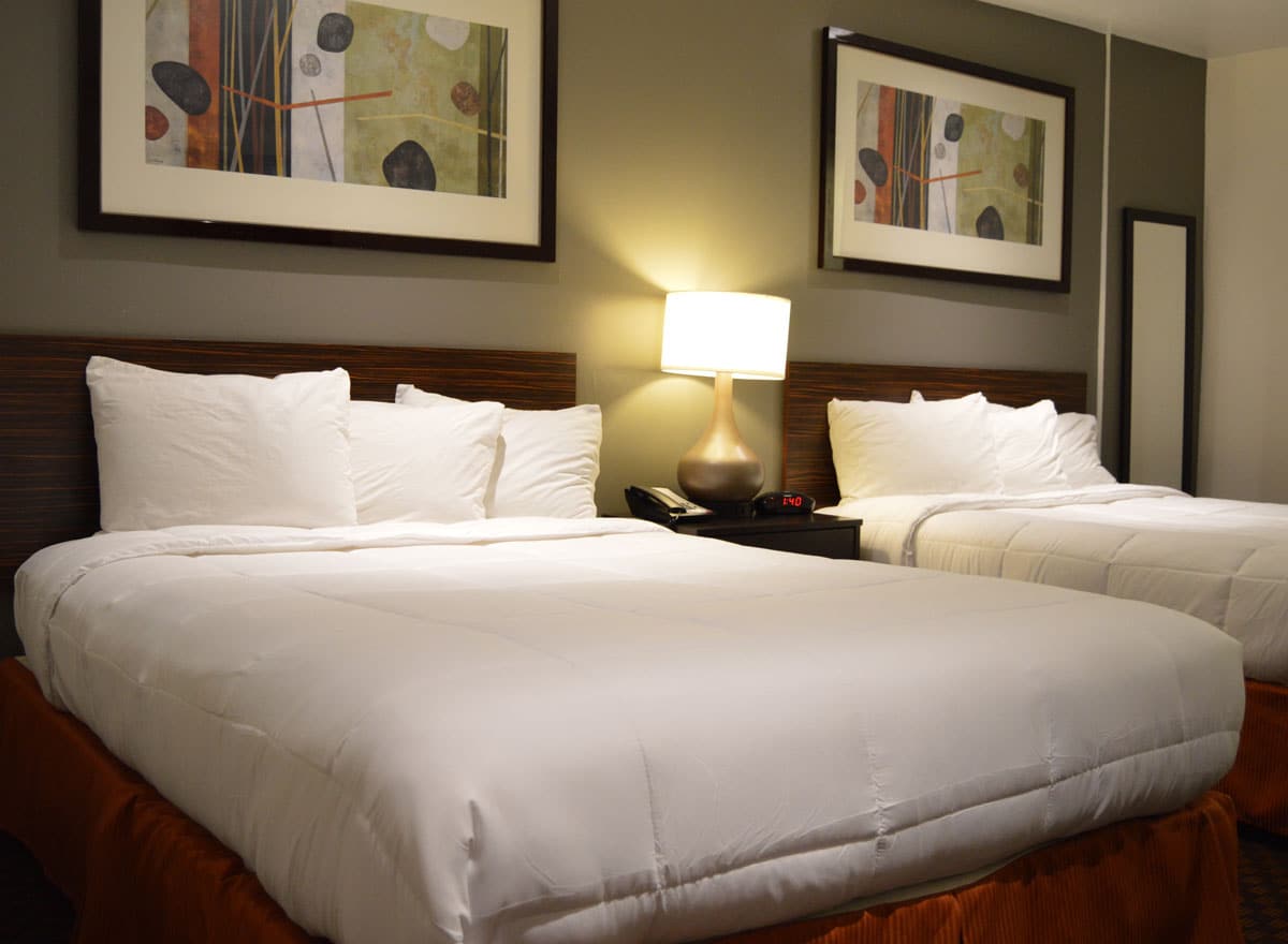 Hotel room with two double beds, white bedding, and warm lighting
