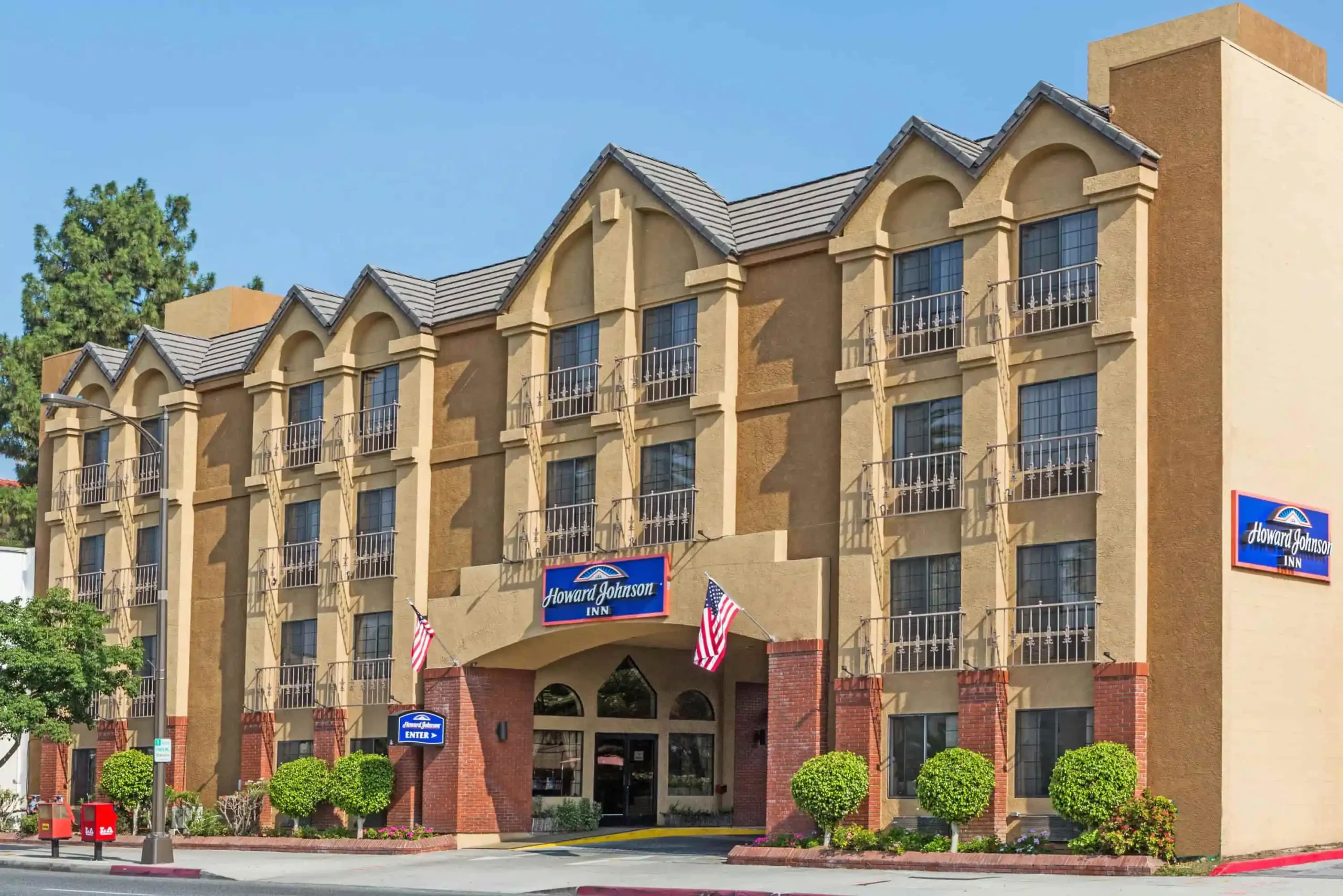 Exterior view of Howard Johnson Pasadena hotel with multiple floors and American flags