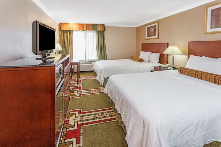 Comfortable hotel room with two queen beds, TV, and warm lighting at Howard Johnson Pasadena
