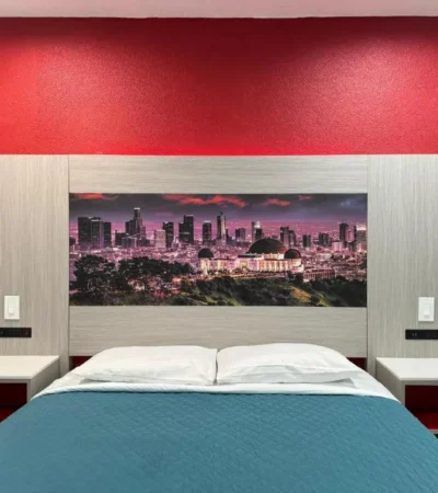 Cozy room at Lincoln Motel Pasadena with red wall, city artwork, and double bed.