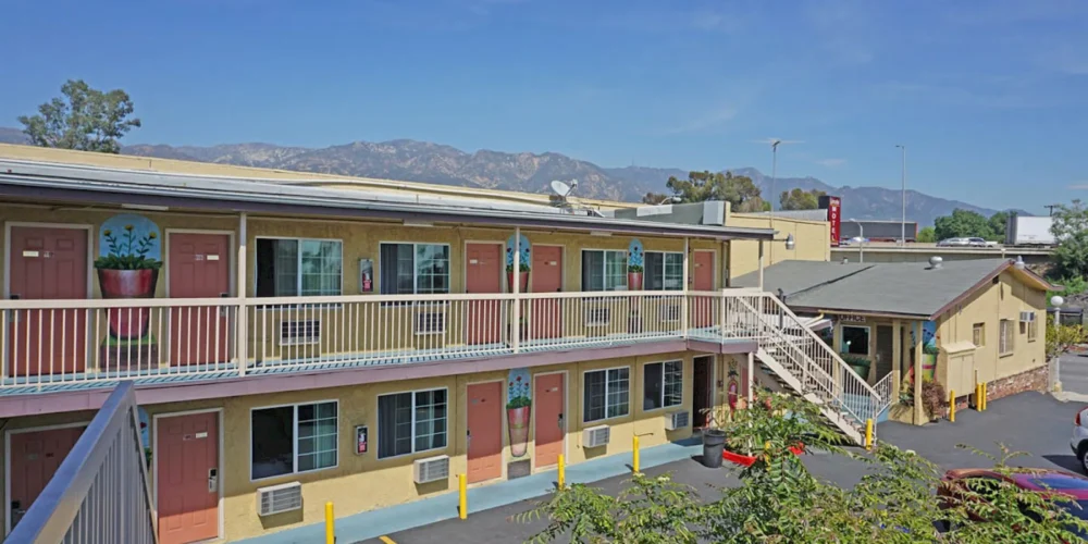 Exterior view of Lincoln Motel Pasadena with two floors and mountain background.