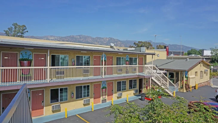 Exterior view of Lincoln Motel Pasadena with two floors and mountain background.