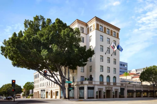 Exterior view of Pasadena Hotel with flags and tree on Colorado Boulevard