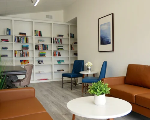 Cozy reading lounge with bookshelves and modern seating at Pasadena Villa Senior Living.