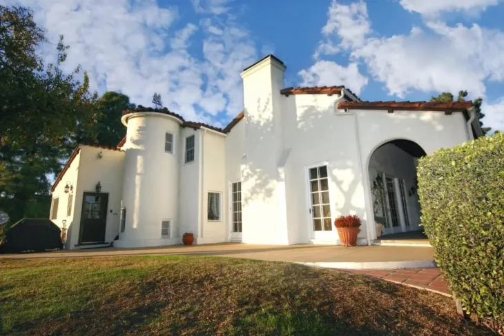 White Spanish-style exterior of The Patrician Hollywood Universal guesthouse with arched entry and terracotta roof under blue Pasadena skies