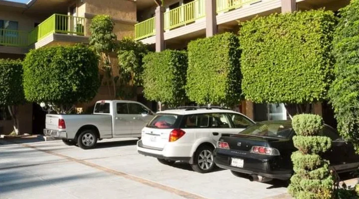 Exterior view of Best Western Plus Glendale with courtyard parking and trimmed green trees in Eagle Rock, Los Angeles.