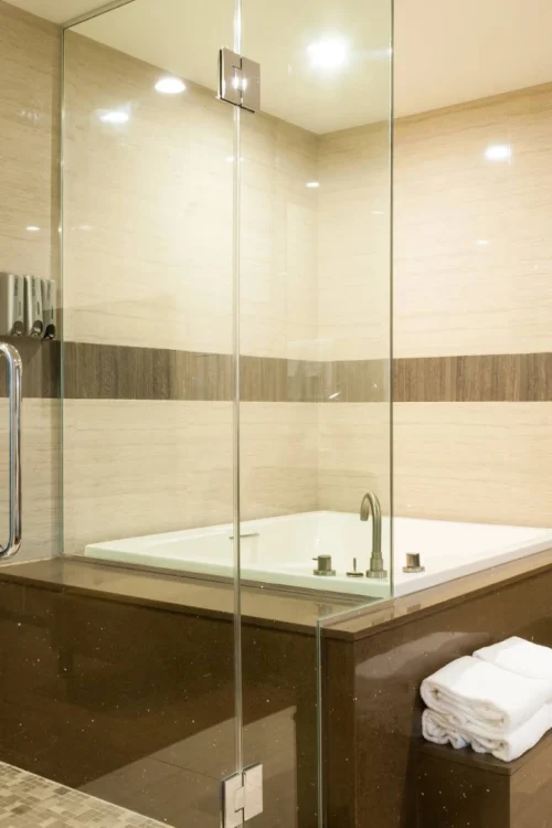 Modern bathroom at Best Western Plus Glendale featuring glass enclosure and large jetted tub with folded towels.