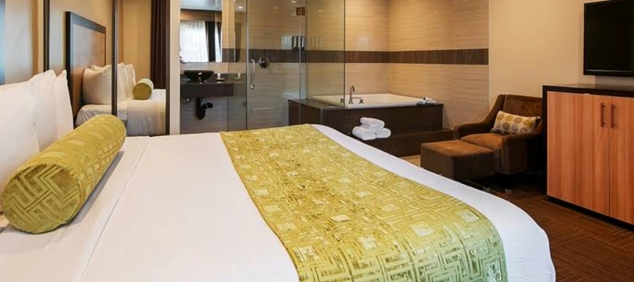 Spacious king room at Best Western Plus Glendale with open spa-style bathroom and soaking tub behind glass.