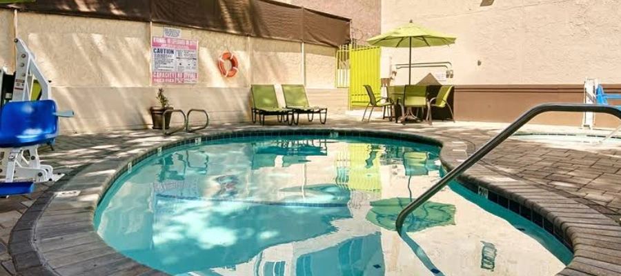 Outdoor pool area at Best Western Plus Glendale with lounge chairs, umbrellas, and pool lift.