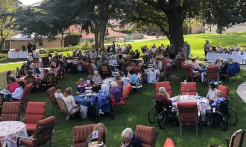 Residents and guests gathering outdoors at The British Home in Sierra Madre for a community garden event