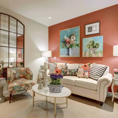 Elegant resident lounge with warm coral accent wall and floral decor at The Kensington Sierra Madre