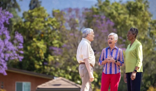 Residents chatting outdoors among blooming trees at Royal Oaks senior community Duarte CA