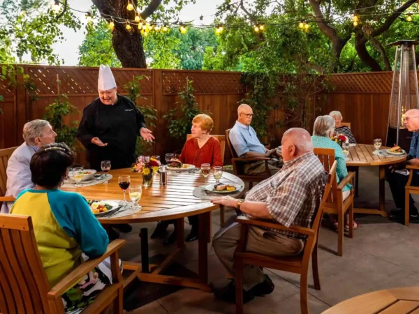 Chef serving dinner to residents on outdoor patio at Royal Oaks Duarte CA