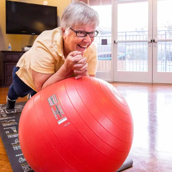 Active resident using exercise ball in fitness center at Royal Oaks Duarte CA
