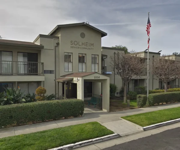 Exterior view of Solheim Senior Community entrance on Merton Avenue with flag and landscaped walkway
