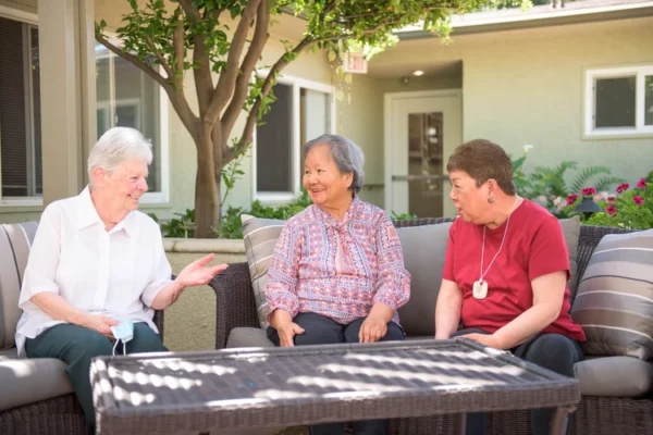 Three residents talking together on outdoor sofas in the Solheim courtyard seating area
