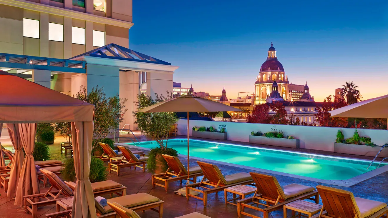 Rooftop pool with lounge chairs and Pasadena City Hall view at sunset at The Westin Pasadena.