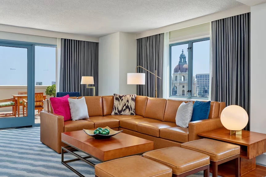 Spacious suite living room with leather sofa and view of Pasadena City Hall at The Westin Pasadena.
