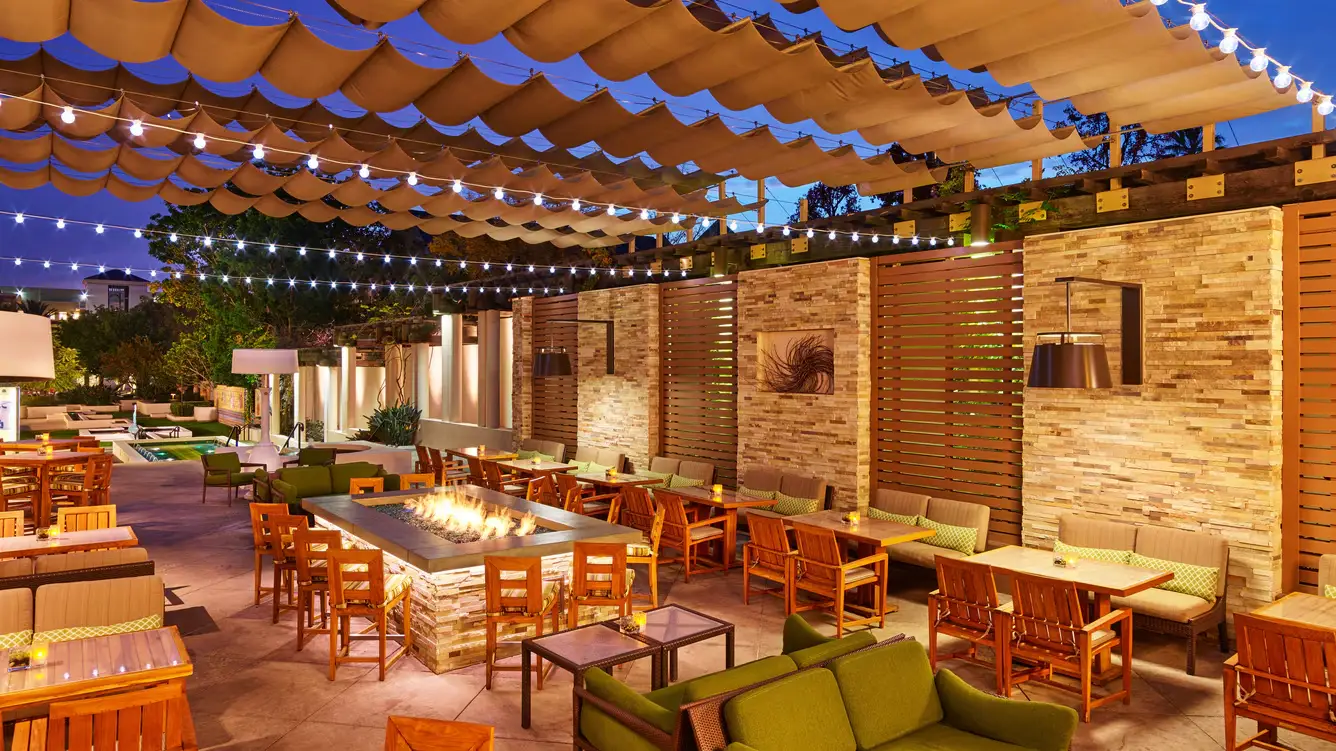 Outdoor dining terrace of Ventanas Restaurant & Bar with firepit and string lights at The Westin Pasadena.