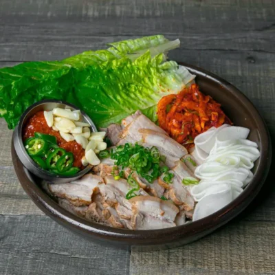 Korean bossam platter with sliced pork, lettuce leaves, kimchi, garlic and peppers