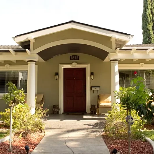 Exterior view of the Montevista Garden Residential Care Facility, showing the front entrance with the house number 1812, a red front door, and a well-maintained, landscaped lawn and walkway.