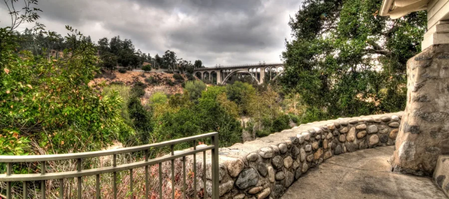 View from La Casita del Arroyo terrace overlooking the Arroyo Seco canyon and historic Colorado Street Bridge behind a stone wall.