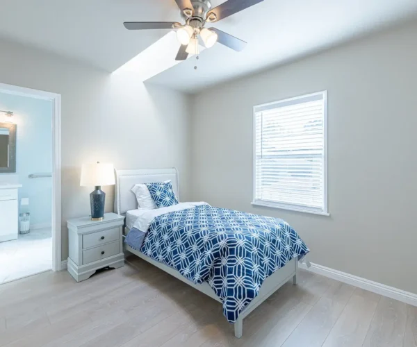 Private resident bedroom at Rose Valley Garfias featuring natural light, ceiling fan, and a calm, home-like assisted living environment
