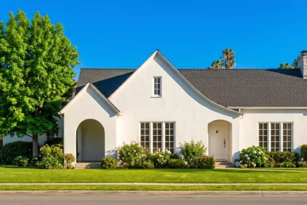 A perfectly centered, straight-on front-facing composition illuminated by bright, warm natural daylight. The image features high contrast, sharp clarity, and vibrant color richness, juxtaposing a pristine, cloudless blue sky with impeccably lush, saturated green foliage and a crisp white architectural facade. Soft, realistic shadows cast gracefully across the manicured lawn, creating a clean, highly professional, and visually inviting aesthetic. No text is visible on the structure.